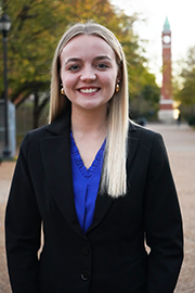 A headshot photo of Claire Leingang with a clocktower and trees in the background.