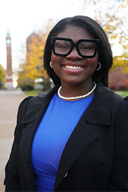 A headshot photo of Kaia Pritchett with a clocktower and trees in the background.