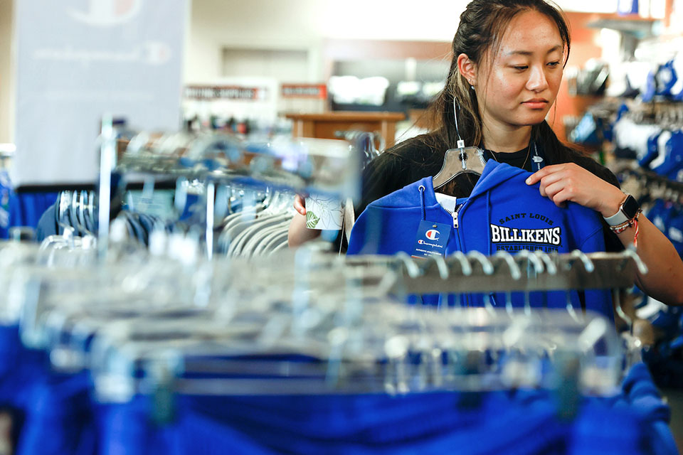 A student looks through clothing items at the bookstore.