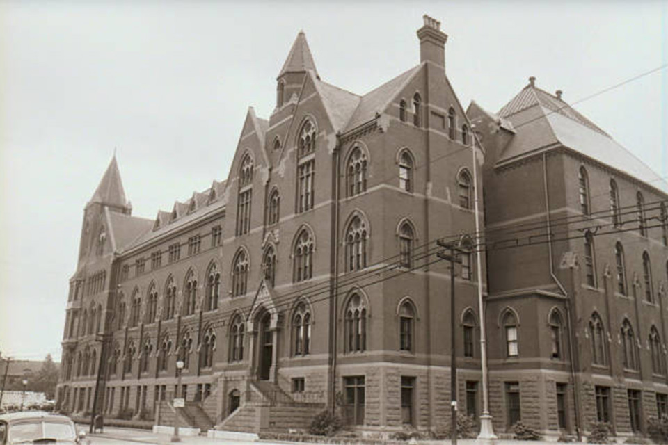 An old photo of a large brick building on campus.