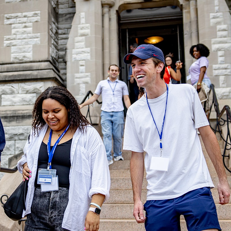 Two students walk down the steps of St. Francis Xavier College Church, talking and smiling.