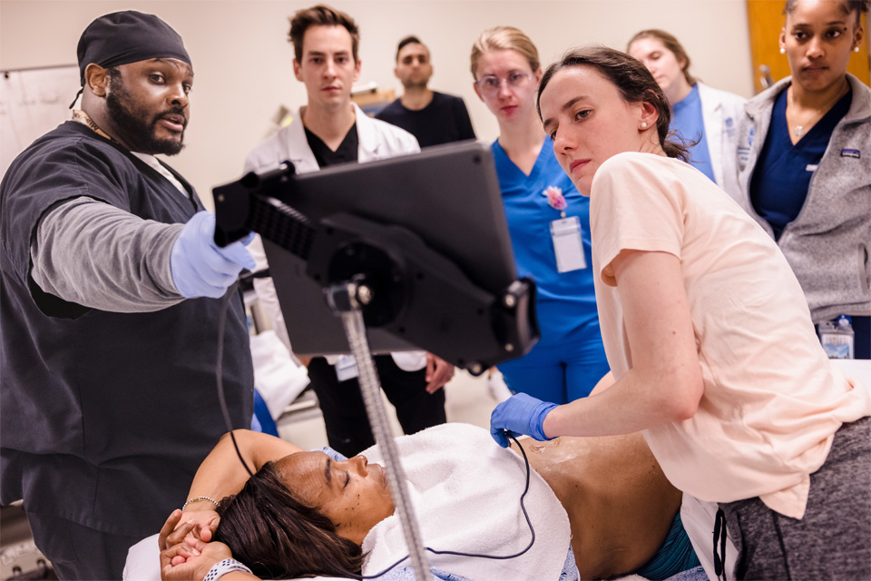 A group of students with their instructor learning on a live test patient