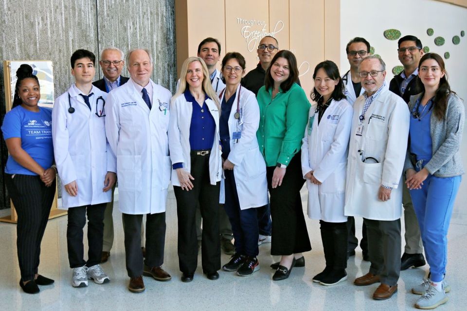 Department faculty pose for a group photo in the hallway of a SLU School of Medicine building.