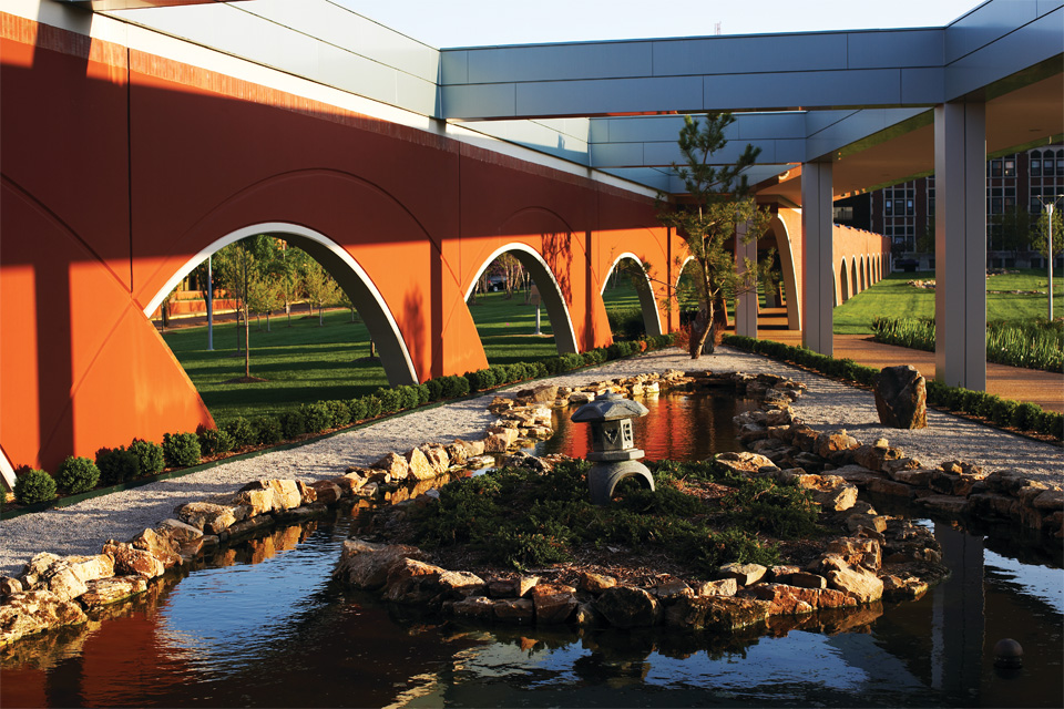 Photo shows the outside of the arched walkway heading from Doisy Hall looking at a Garden. 