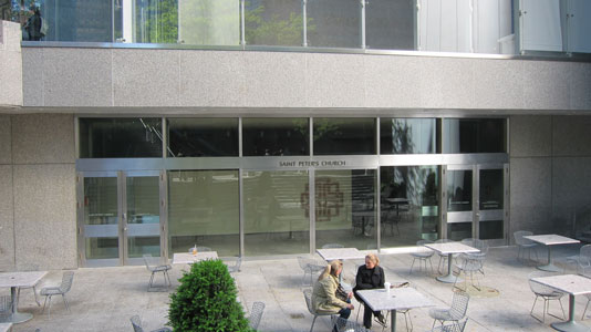 People sit at outdoor tables in the plaza outside the former entrance to St. Peter's Lutheran Church