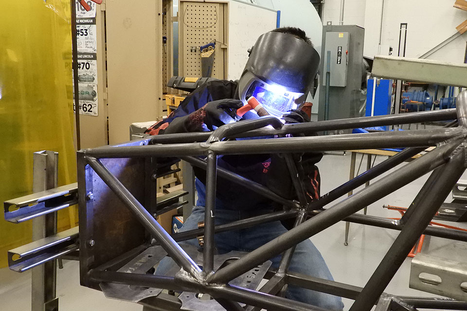 Junior Jacob Bullard welds a part onto the chassis of the Parks Racing FASE Car in Oliver Hall at Saint Louis University.