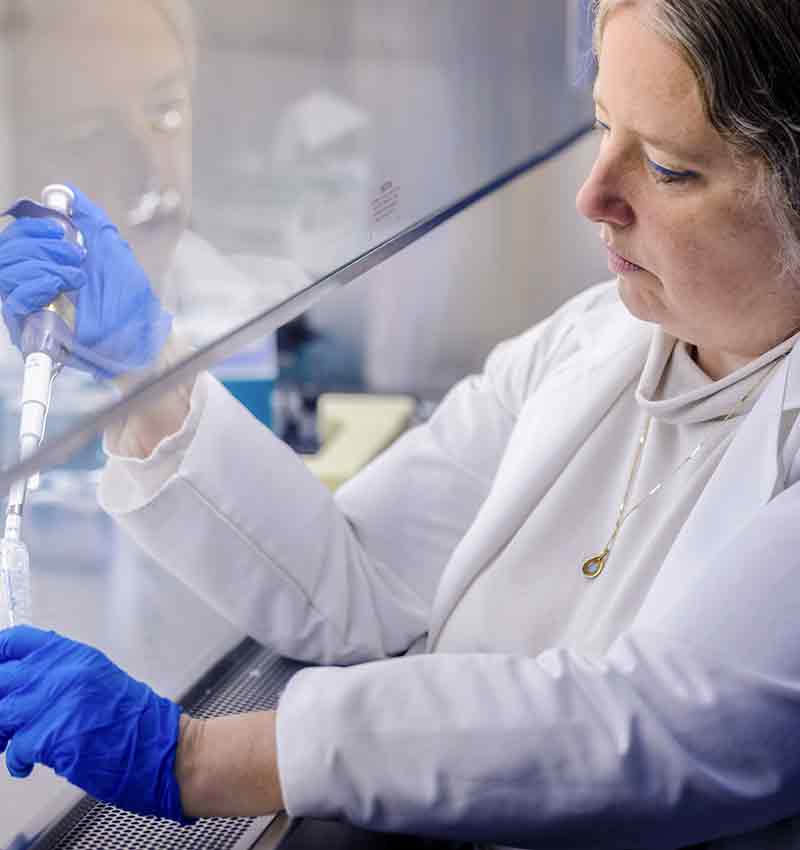 Sarah George, a SLU researcher, works with a specimen works with a material underneath a lab hood.