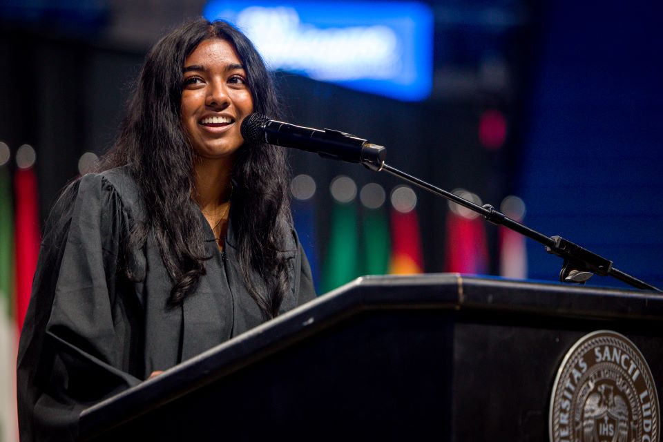 A woman gives a speech at a podium.