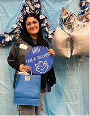 Sara Mosavi stands next to star-shaped balloons, holding a sign that reads "I am a BIlliken"