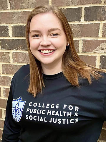 Female studnet with black college for public health and social justice shirt.