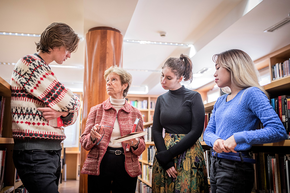 Encinar stands with students in discussion in a library.