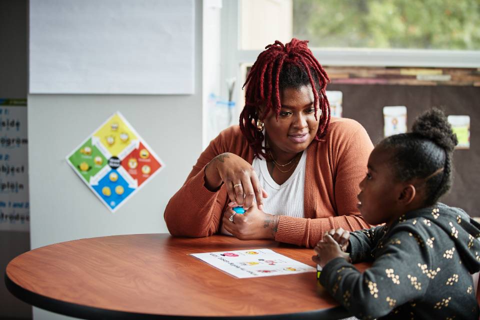 Professional social worker or analyst sitting at a table working with a child