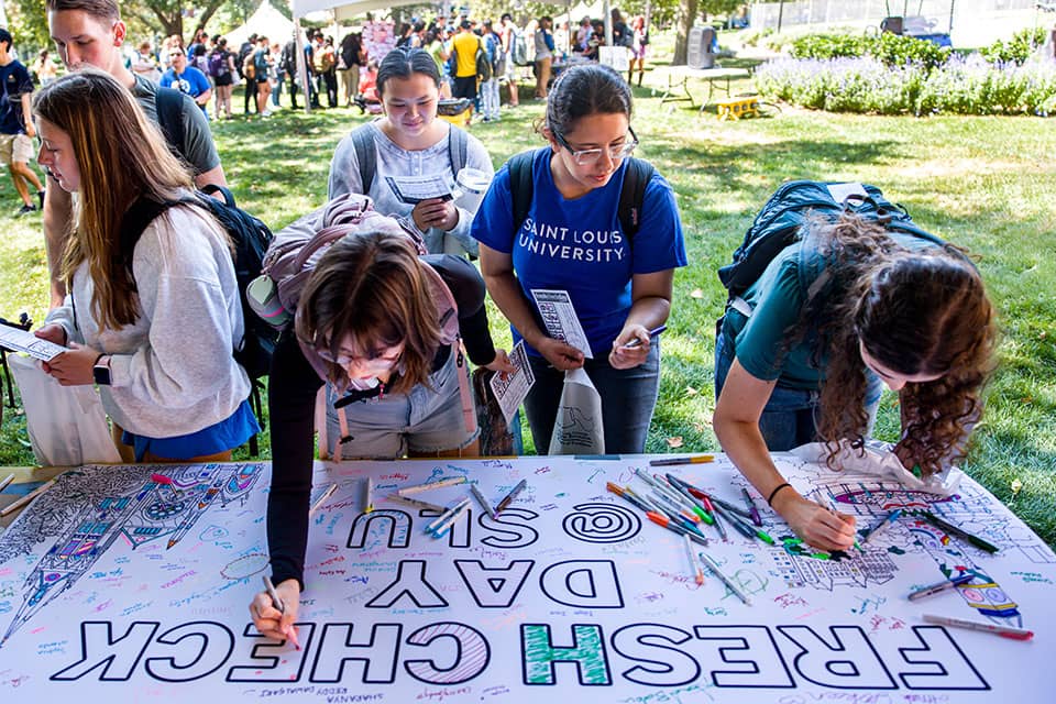 Students sign and color a banner during Fresh Check Day.